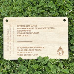 Plaquette en bois gravée, avec message bilingue sur le remplacement des serviettes dans un établissement écoresponsable. Le message est personnalisable selon vos besoins.