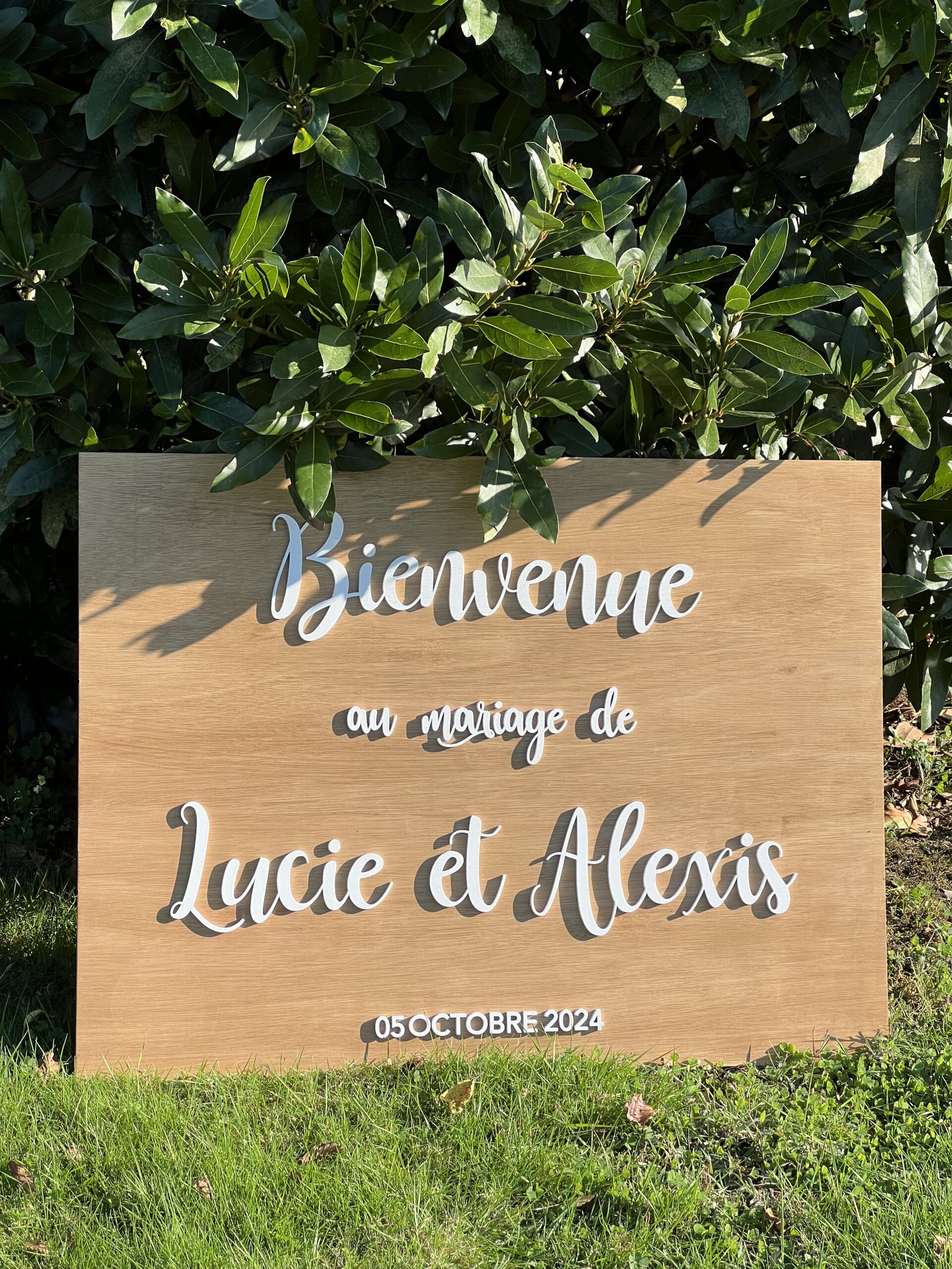 Panneau de bienvenue en bois personnalisé avec prénoms des mariés en lettres relief.